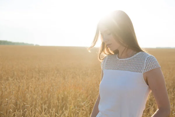 Hübsche junge Frau im Feld bei Sonnenuntergang. — Stockfoto