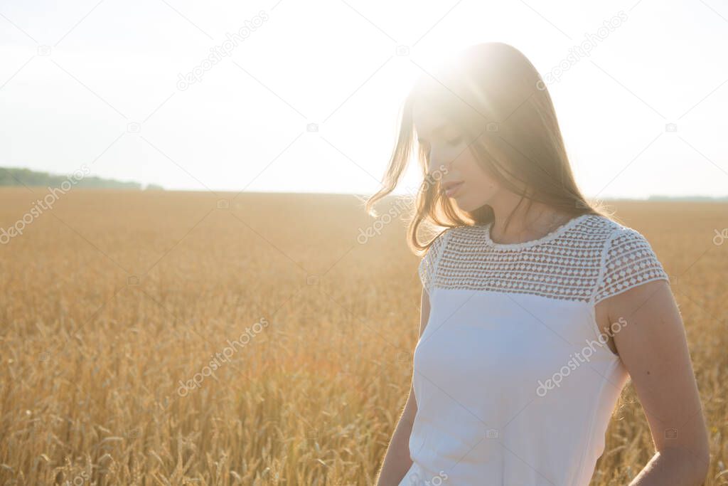 Pretty young woman in field at sunset.