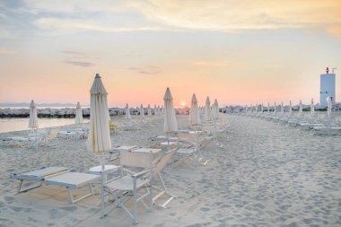 İtalya 'da gün batımında şemsiyeli beyaz kumsal ve güneş ışığı