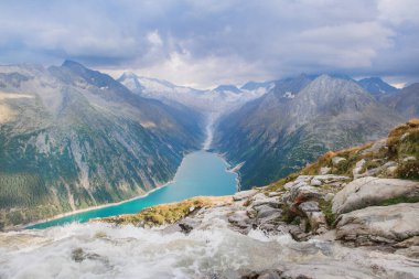 Avusturya 'daki mavi gölün arka planında akan dağ nehri. Zillertal Alpler 
