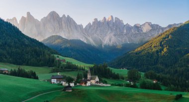 Dolomitlerdeki Aziz Magdalena Kilisesi Panoraması. Tepelerdeki yeşil çimenler ve hangi dağın arkasındaki antik kilise. Güney Tyrol, Val di Funes, İtalya 'da Dolomites Alpleri