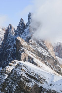 Kışın Dolomitlerde Seceda Dağı. Bulutların üzerinde yüzdüğü karlı kayalık yamaçlar