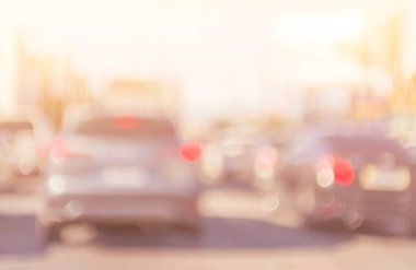 Şehir trafiği bulanık arkaplan ve gün batımı zamanı. Bulanık şehir merkezindeki araçlar trafiğin en yoğun olduğu saatte yolda ilerliyor. Otobanda trafik sıkışıklığı, araba ışıkları, parlak ışık bokeh taşıma aracı