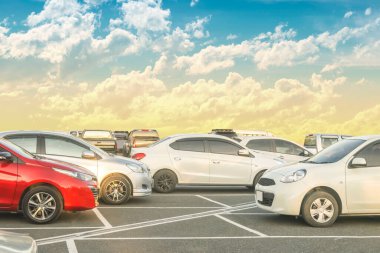 Güzel bulutlar ve günbatımı arka planıyla büyük bir asfalt otoparka park edilmiş bir araba. Açık hava otoparkı seyahat teknolojisi ve doğa kavramı.