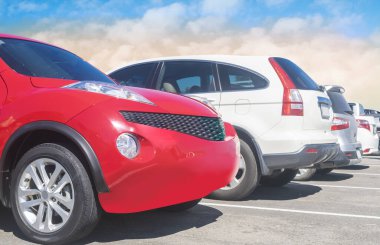 Beyaz bulutlu ve mavi gökyüzü arka planlı büyük bir asfalt otoparka park edilmiş bir araba. Açık hava otoparkı seyahat teknolojisi konsepti