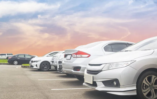 Car parking in large asphalt parking lot with beautiful sky background. Outdoor parking lot with nature fresh ozone and green environment of travel transportation business concep