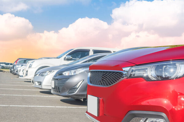 Car parked in large asphalt parking lot with white cloud and blue sky background. Outdoor parking lot  travel transportation technology concept. Front view of red car