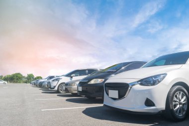 Beyaz bulutlu ve mavi gökyüzü arka planlı büyük bir asfalt otoparka park edilmiş bir araba. Açık hava otoparkı seyahat teknolojisi konsepti. 