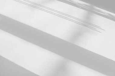 Pencerenin beyaz duvarında gri gölge ve ışık bulanık arkaplan. Mimari çizgiler. Salonun arka planında koyu gölgeler. Monokrom.