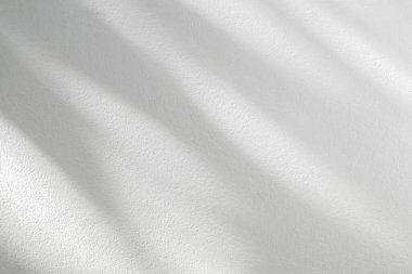 Yaprağın soyut ışık gölgesi arkaplanı bulanıklaştırıyor. Beyaz duvarda doğal çapraz yapraklar, ağaç dalları gölgeler ve güneş ışığı. Gölge kaplama efekti yeşillik alaycısı