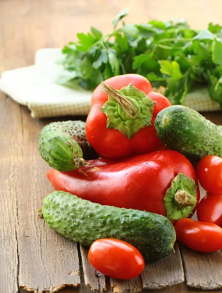 Cucumbers, tomatoes and red peppers on a wooden table — Stock Photo, Image
