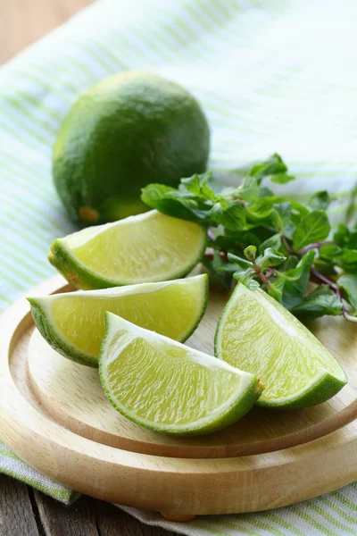 Fresh organic cut limes on wooden table — Stock Photo, Image