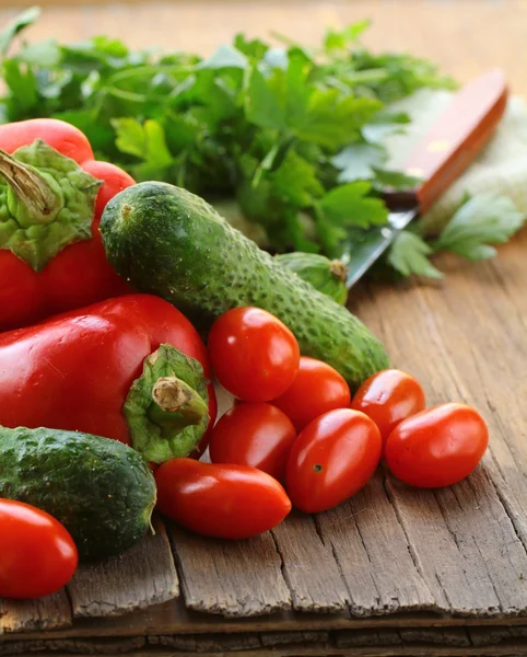 Komkommers, tomaten en paprika op een houten tafel — Stockfoto