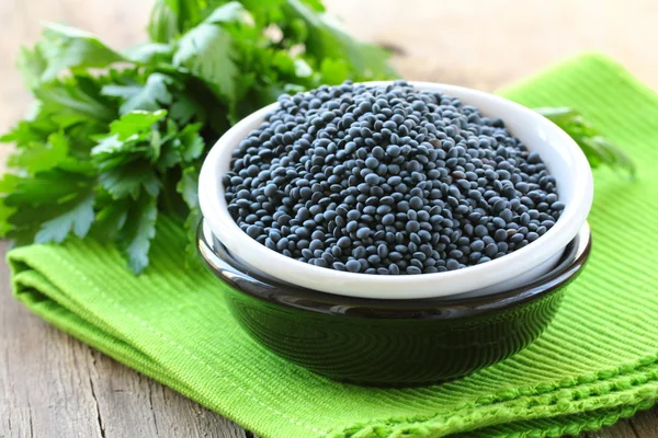 Beluga black lentils in a bowl on a wooden table — Stock Photo, Image