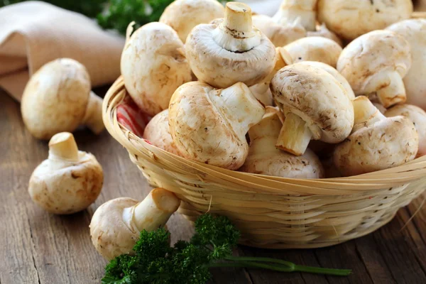 Fresh champignon mushrooms in a wicker basket — Stock Photo, Image