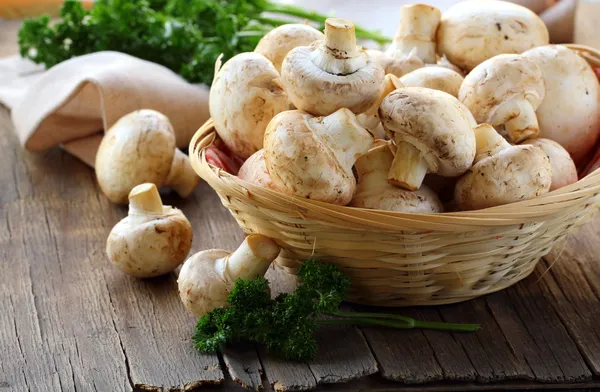 Fresh champignon mushrooms in a wicker basket — Stock Photo, Image