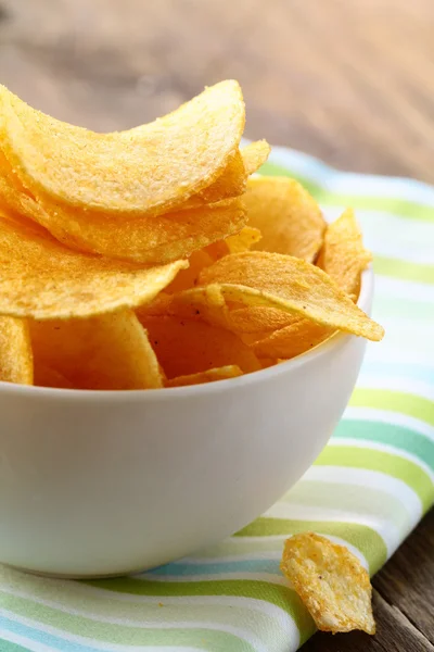 Potato chips in a white bowl on a wooden table — Stock Photo, Image