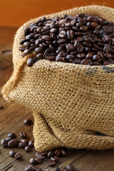 Linen bag with coffee beans on wooden table — Stock Photo, Image