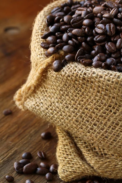 Linen bag with coffee beans on wooden table — Stock Photo, Image