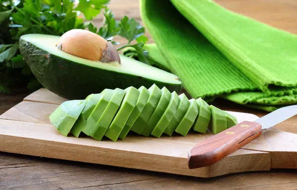 Aguacate pelado limpio maduro cortado en rodajas en el tablero — Foto de Stock