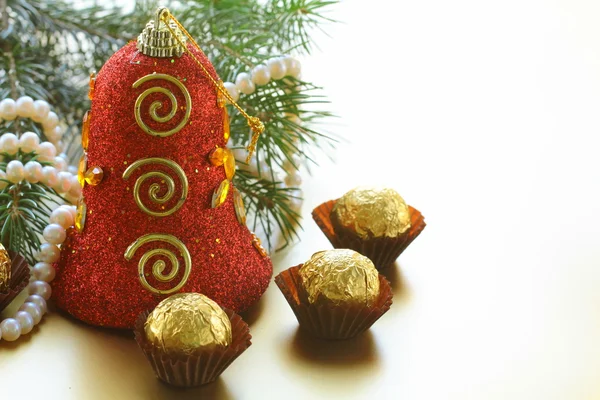 Christmas bell and chocolates with Christmas tree — Stock Photo, Image