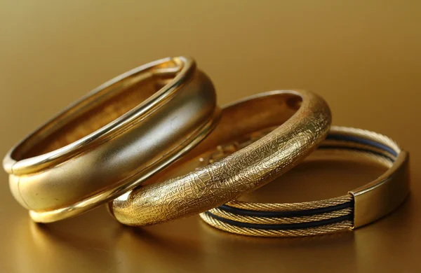 Gold jewelry, bracelets on gold background — Stock Photo, Image
