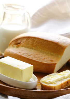 Tereyağ, beyaz ekmek ve süt ahşap plaka üzerinde