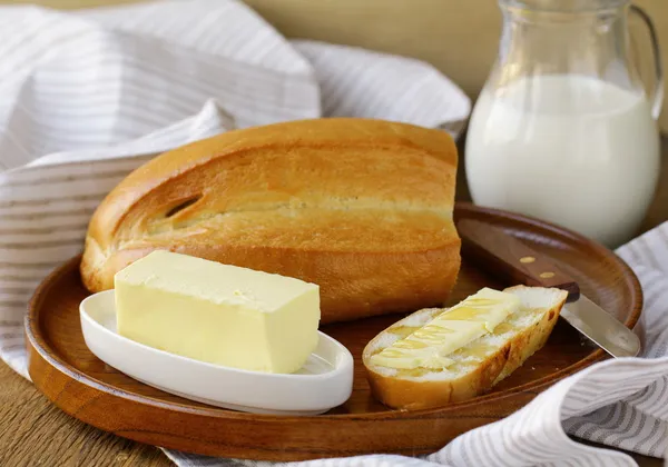 Butter, loaf of white bread and milk on wooden plate — Stock Photo, Image