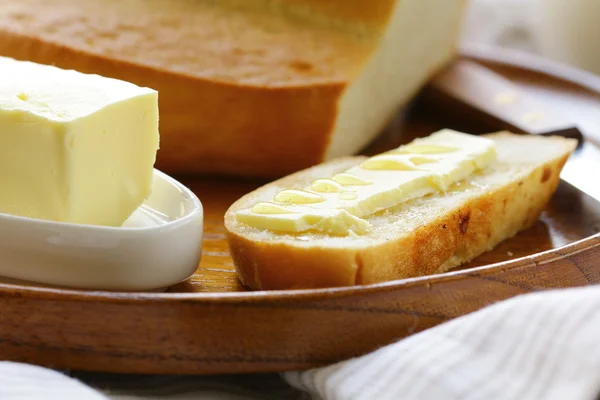 Mantequilla, pan blanco y leche en plato de madera —  Fotos de Stock