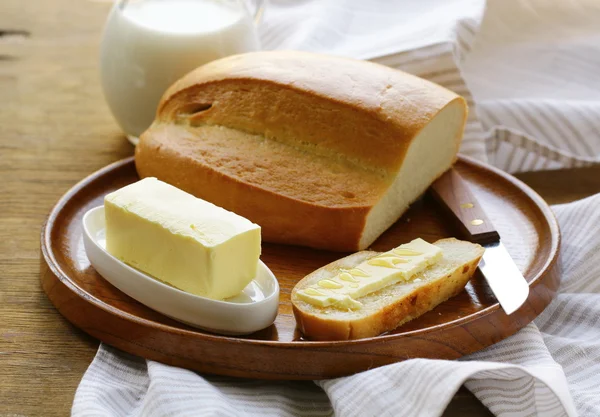 Burro, pagnotta di pane bianco e latte su piatto di legno — Foto Stock