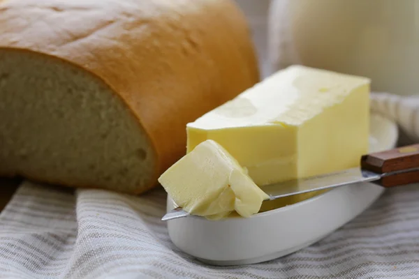Масло, буханка белого хлеба и молоко на деревянном столе — стоковое фото