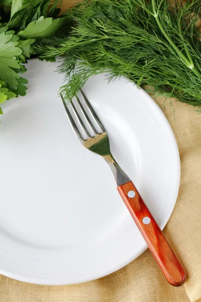 Placa blanca vacía con tenedor sobre mesa de madera con perejil y eneldo — Foto de Stock