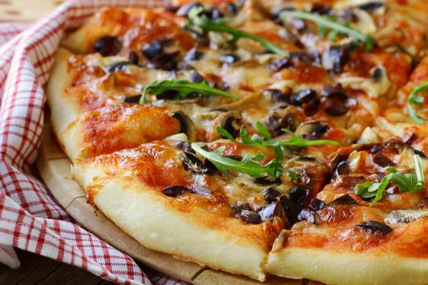 Italian pizza with mushrooms and olives on a wooden board