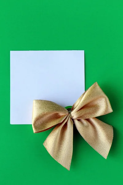 Біла пляма з золотим бантом на зеленому фоні — стокове фото