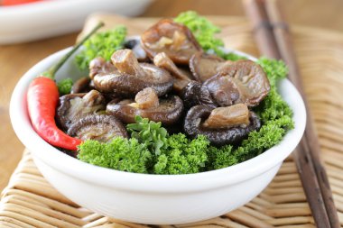 Chinese fried shiitake mushrooms in a bowl with parsley clipart