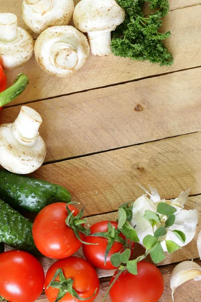 Frame of vegetables (cucumber, tomato,mushrooms, garlic) on a wooden background — Stock Photo, Image