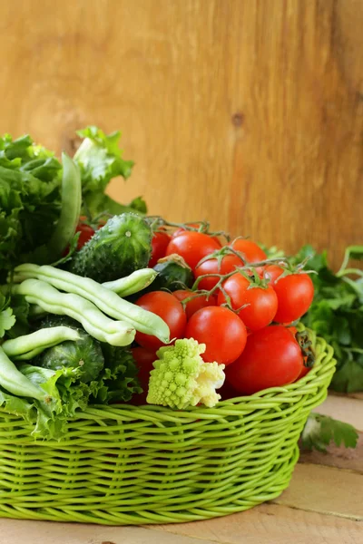 Legumes frescos (pepinos, tomates, repolho romanesco e feijão verde) e ervas se misturam em uma cesta de vime — Fotografia de Stock