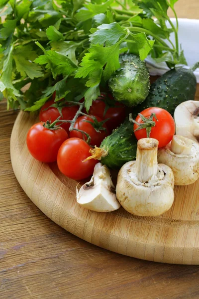 Tomates, pepinos, cogumelos e salsa em uma tábua de redução — Fotografia de Stock