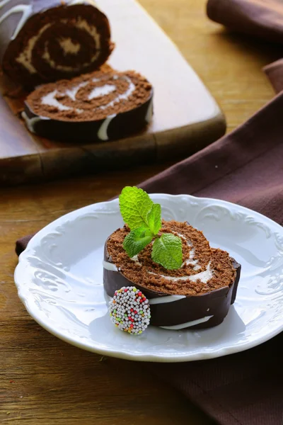 Rolo de bolo de chocolate com creme de baunilha em uma placa de madeira — Fotografia de Stock