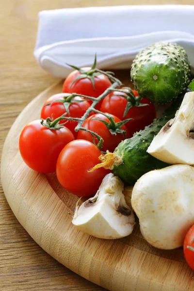 Tomaten, komkommers, paddestoelen en peterselie op een snijplank — Stockfoto