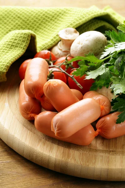 Fresh sausages and parsley on wooden cutting board — Stock Photo, Image