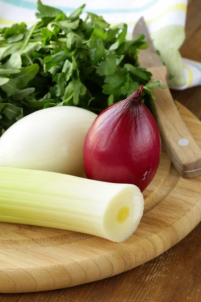 Various types of onions (leeks, red and white) on the cutting board — Stock Photo, Image