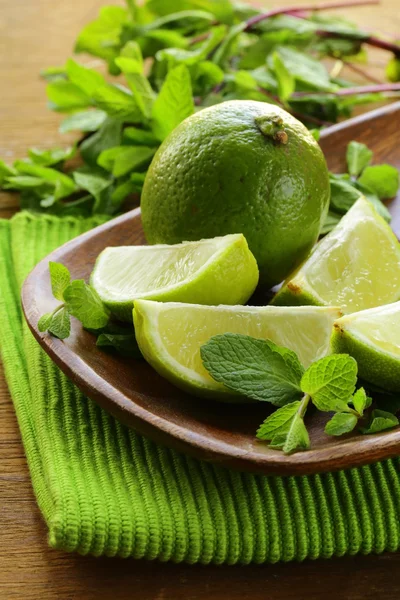 Fresh organic cut limes on wooden plate — Stock Photo, Image