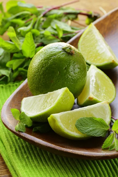 Fresh organic cut limes on wooden plate — Stock Photo, Image