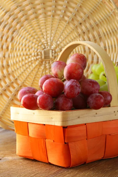 Piros és zöld szőlő egy fonott kosárban — Stock Fotó