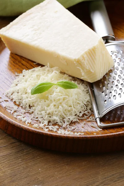 Ralado queijo parmesão e ralador de metal em placa de madeira — Fotografia de Stock