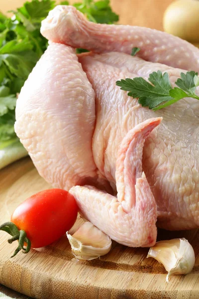 Färsk rå kyckling på en skärbräda med grönsaker och örter — Stockfoto