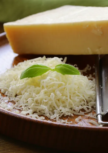 Ralado queijo parmesão e ralador de metal em placa de madeira — Fotografia de Stock