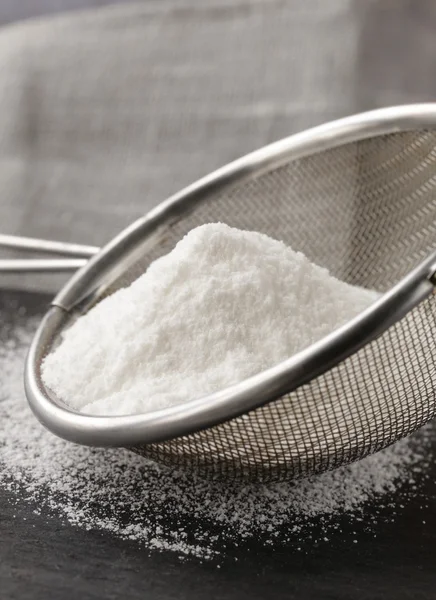 Powdered sugar in a metal strainer on a gray background — Stock Photo, Image