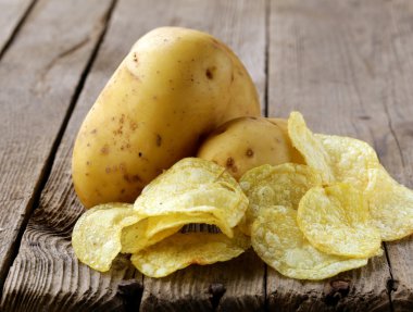 doğal patates cipsi ve ahşap zemin üzerine taze patates